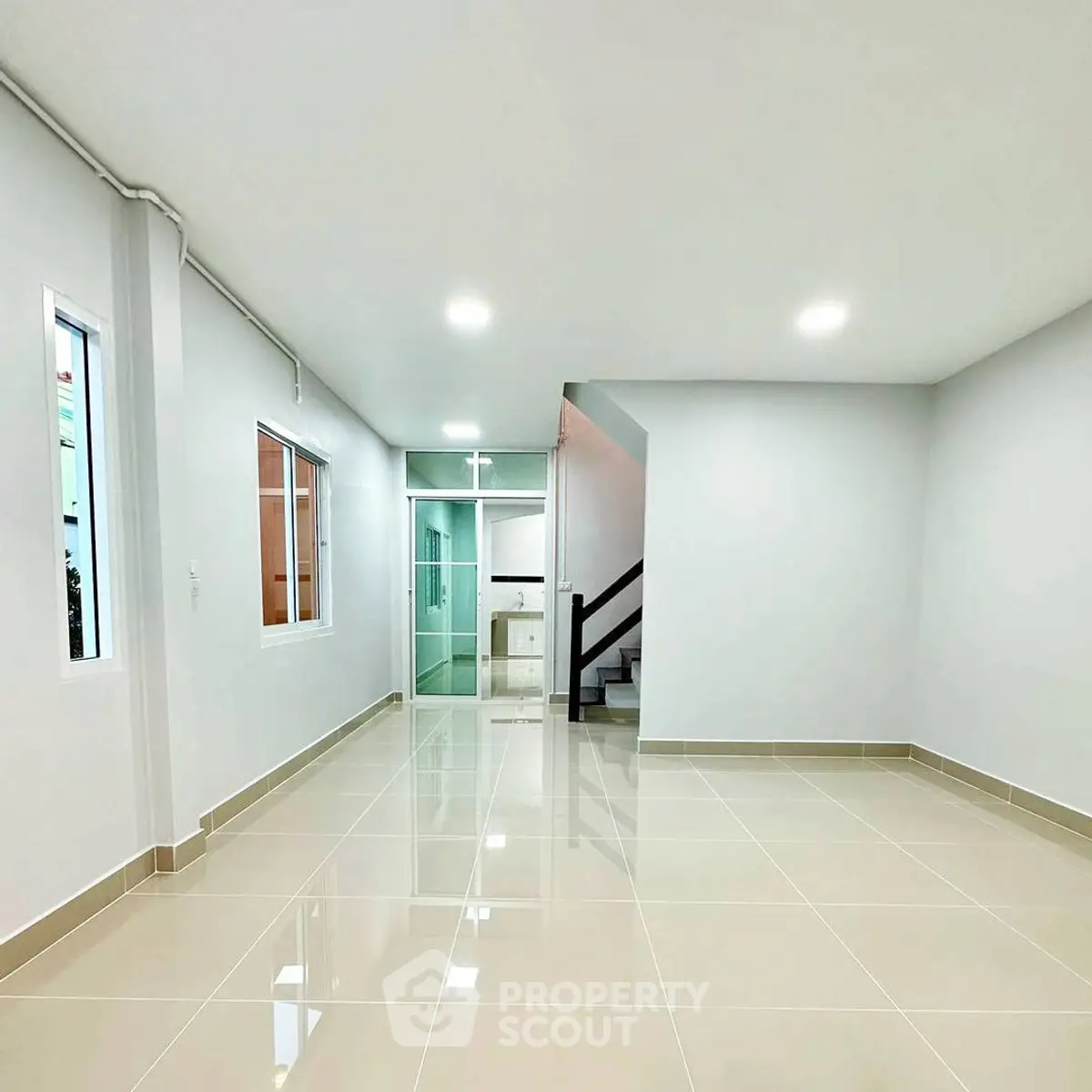 Spacious modern living room with glossy tiled floors and staircase