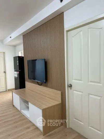 Modern living room with sleek wooden paneling and mounted TV, showcasing minimalist design and elegance.