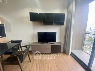 Modern living room with sleek TV unit and city view balcony in high-rise apartment.