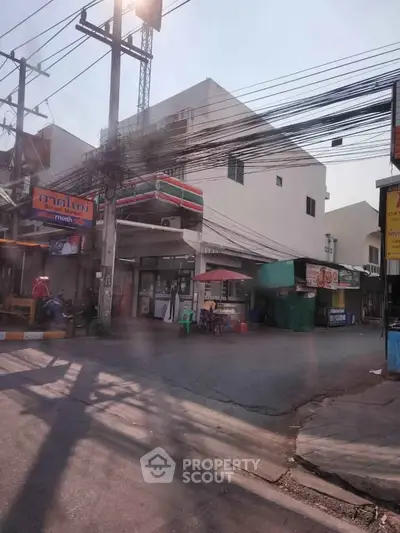 Street view of a commercial building with convenience store and food stalls in urban area.