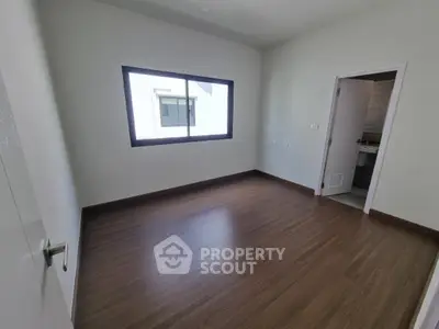 Spacious bedroom with wooden flooring and ensuite bathroom in modern home