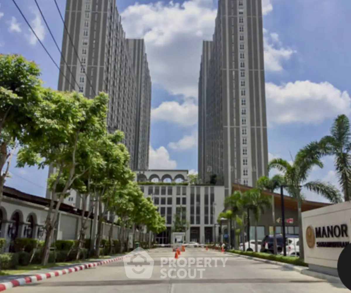 Stunning high-rise building entrance with lush greenery and clear blue sky.