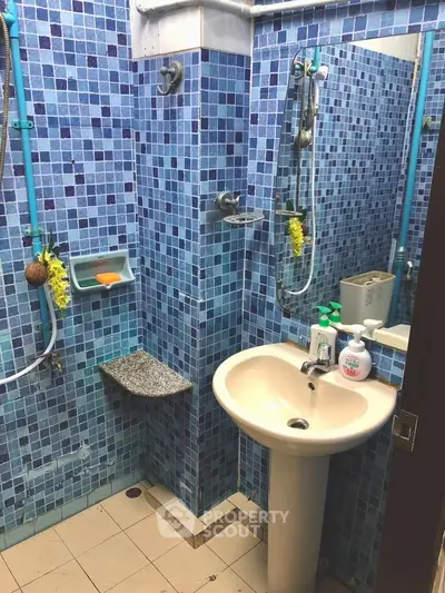 Compact bathroom with blue mosaic tiles and pedestal sink