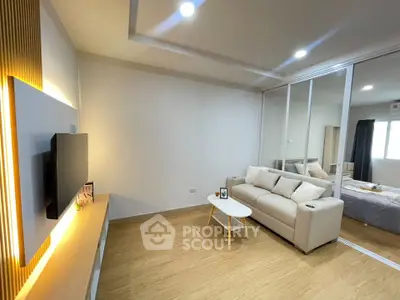 Modern living room with cozy sofa and stylish decor adjacent to a bedroom with natural light.