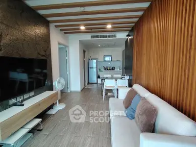 Modern living room with open kitchen, wooden accents, and sleek design.