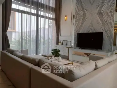 Luxurious living room with high ceilings, marble accent wall, and large sectional sofa.