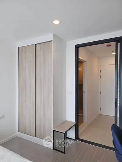 Modern bedroom with sleek wardrobe and minimalist design, featuring a sliding door and neutral tones.