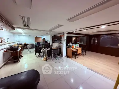 Spacious open-plan office with modern lighting and tiled flooring, ideal for creative workspace.