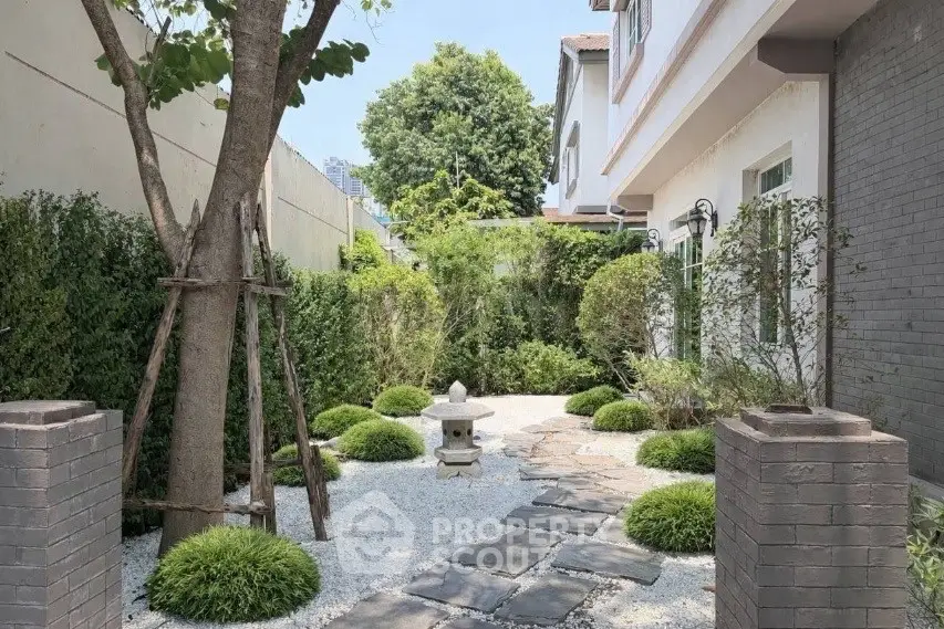 Charming garden pathway with lush greenery and stone lantern in serene residential setting.