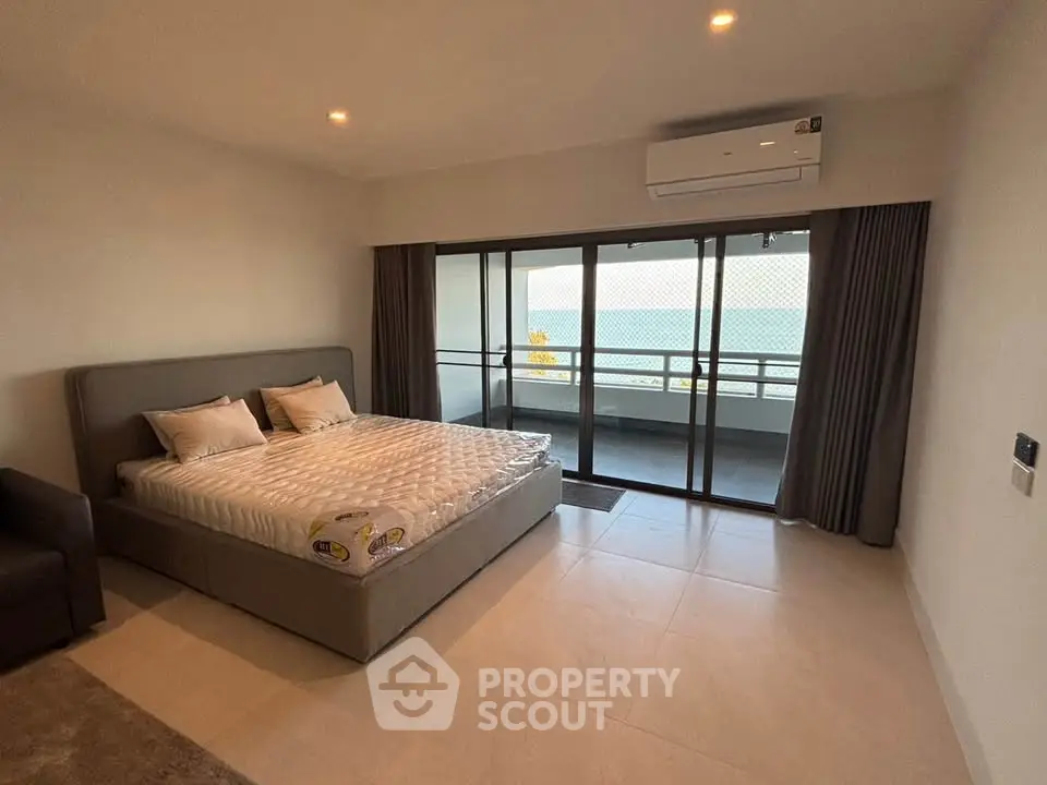 Spacious bedroom with ocean view and large balcony access, featuring modern decor and air conditioning.