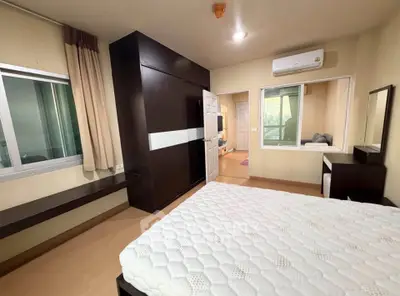 Spacious bedroom with modern furniture and large window offering natural light.