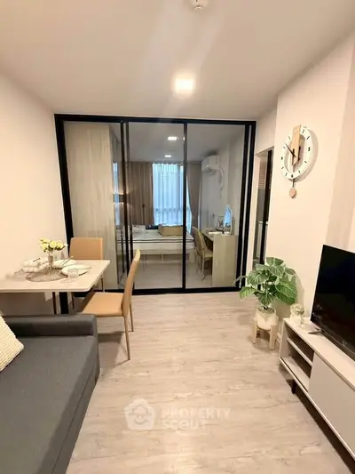 Modern living room with glass partition, stylish decor, and cozy dining area in a contemporary apartment.