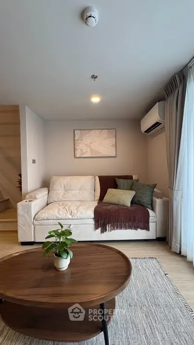 Cozy living room with modern decor, featuring a plush sofa, stylish coffee table, and natural light from large windows.