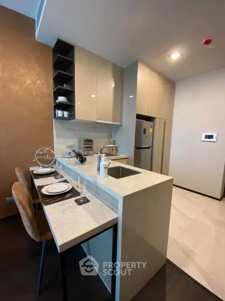 Modern kitchen with sleek design, featuring a breakfast bar and integrated appliances in a stylish apartment.