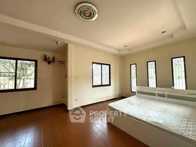 Spacious bedroom with large windows and natural light, featuring a minimalist design and wooden flooring.