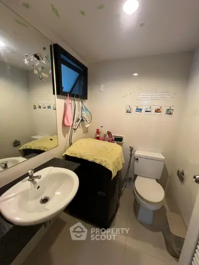 Compact bathroom with modern sink and toilet, featuring wall decorations and storage solutions.