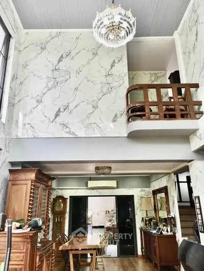 Luxurious living room with high ceilings, elegant chandelier, and marble walls in a sophisticated home.