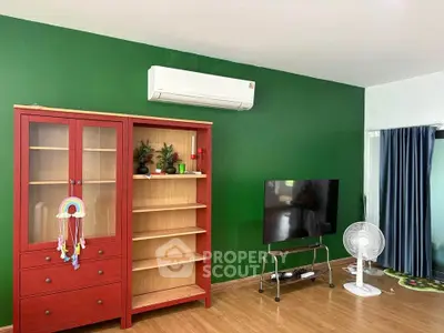 Spacious living room with vibrant green wall, red cabinet, and modern air conditioning unit.
