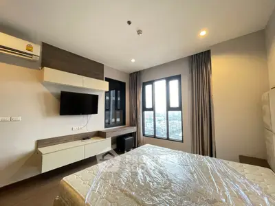 Modern bedroom with large windows and wall-mounted TV in a stylish apartment.