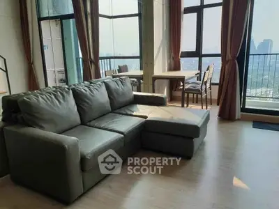Spacious living room with large windows and city view, featuring modern furniture and elegant decor.