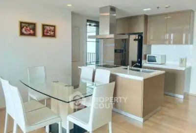 Modern kitchen with dining area featuring sleek glass table and white chairs, perfect for contemporary living.