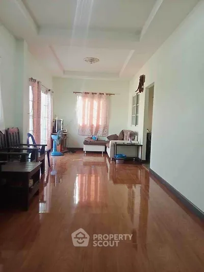 Spacious living room with polished wooden floors and cozy seating area.