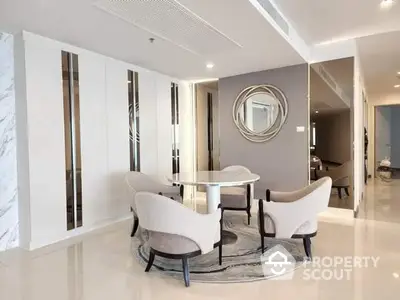 Elegant dining space with modern furniture, sleek marble accents, and a chic circular mirror, seamlessly connecting to a spacious living area.