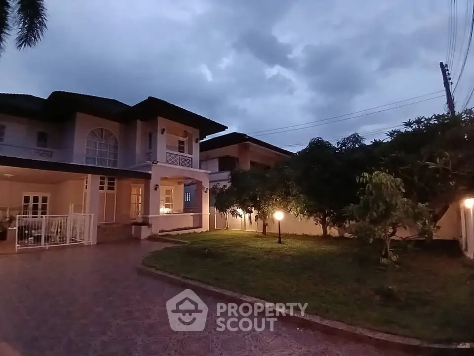 Stunning two-story home with spacious garden and elegant exterior lighting at dusk.