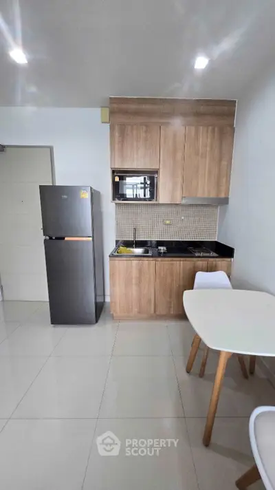 Modern kitchen with sleek cabinetry and compact dining area in a stylish apartment.