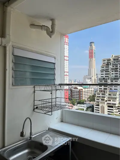High-rise apartment balcony with city view and outdoor sink area.