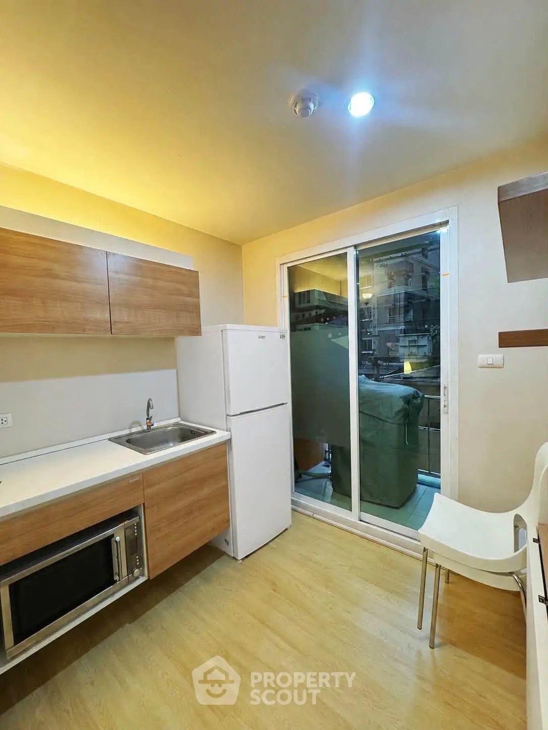 Modern kitchen with sleek cabinetry, built-in microwave, and sliding glass door to balcony.