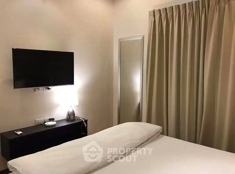 Cozy bedroom with modern TV and elegant curtains, perfect for relaxation.