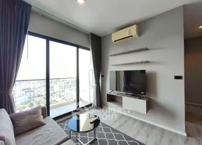 Modern living room with balcony view, featuring sleek furniture and air conditioning.