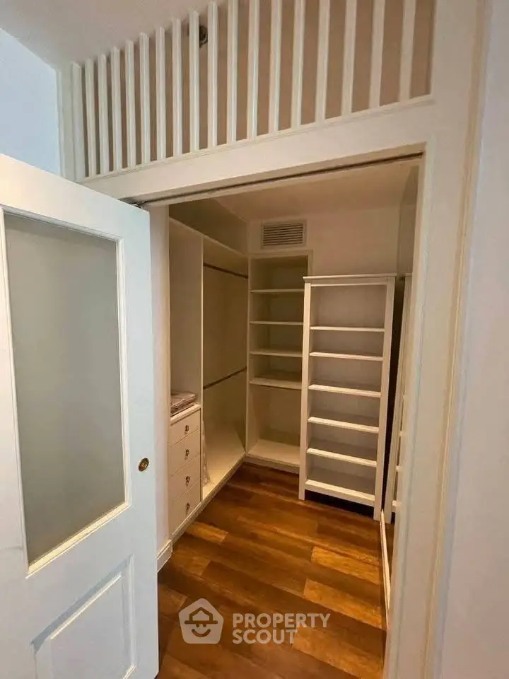 Spacious walk-in closet with wooden flooring and ample shelving in modern home.