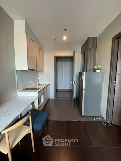 Modern kitchen with sleek cabinetry and dining area in contemporary apartment.