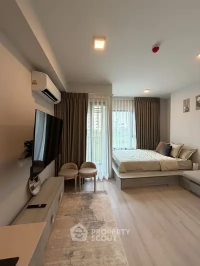 Modern bedroom with large window, stylish decor, and cozy seating area in a contemporary apartment.