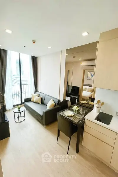 Modern living room with open kitchen in a stylish apartment, featuring sleek furniture and natural light.