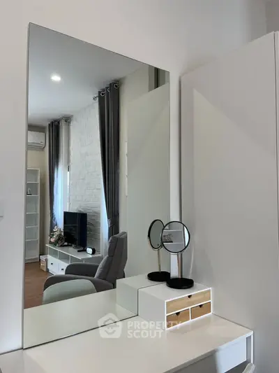 Modern living room with stylish decor and large mirror reflecting cozy seating area.