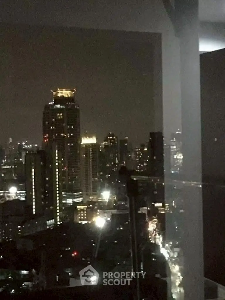 Stunning cityscape view from a high-rise balcony at night, showcasing vibrant urban lights.