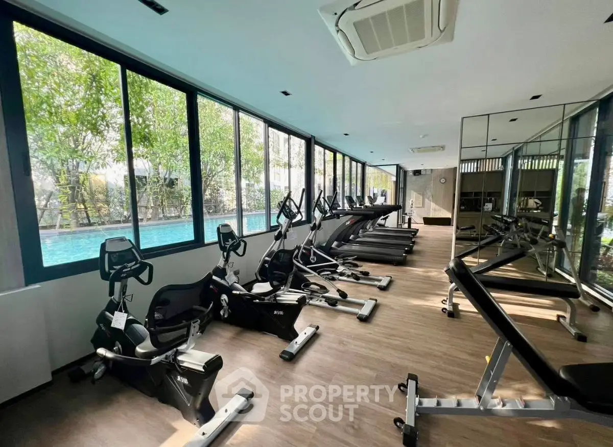 Modern gym with state-of-the-art equipment and pool view in luxury residential building.