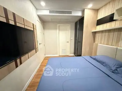 Modern bedroom with stylish decor and large wall-mounted TV