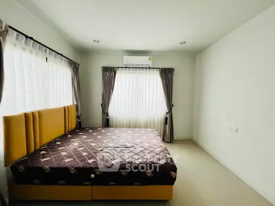 Spacious bedroom with large windows and modern air conditioning unit, perfect for comfort and relaxation.