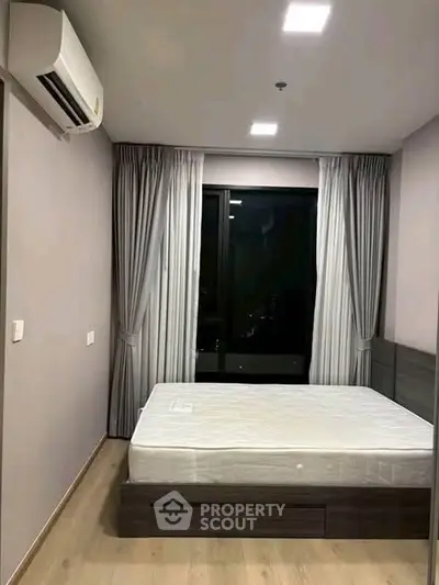 Modern bedroom with sleek design, featuring a comfortable bed and large window for natural light.