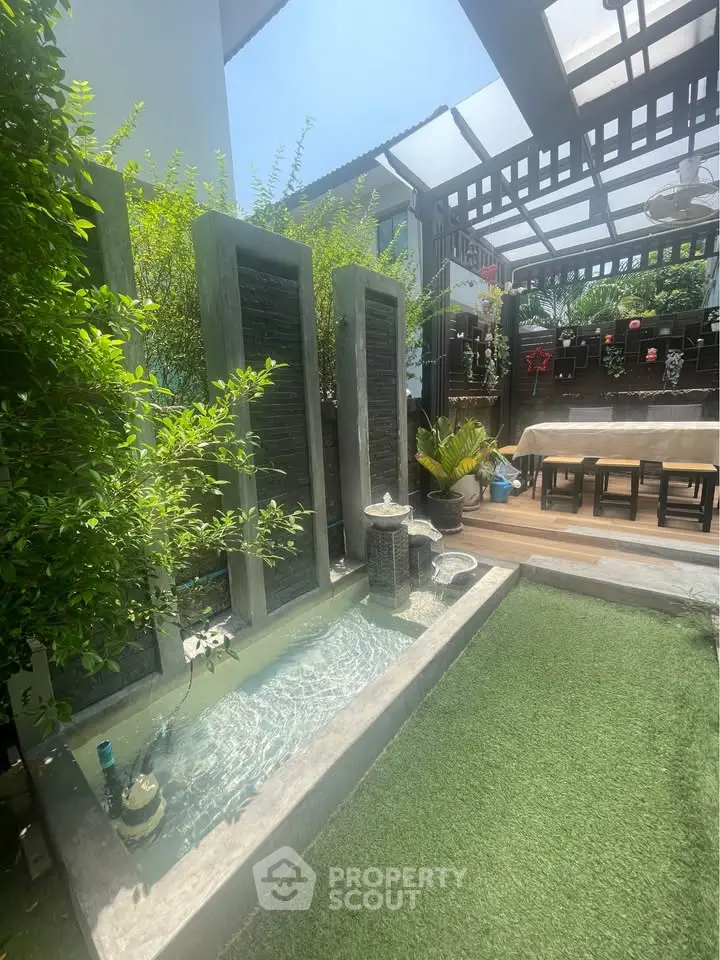 Charming outdoor garden with water feature and covered dining area, perfect for relaxation and entertaining.