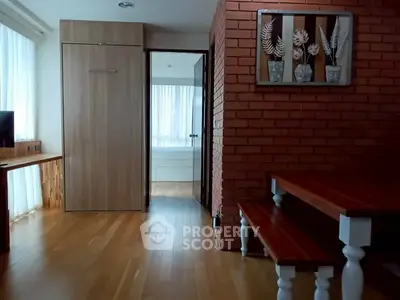 Charming interior with wooden floors, brick accent wall, and natural light, perfect for cozy living.