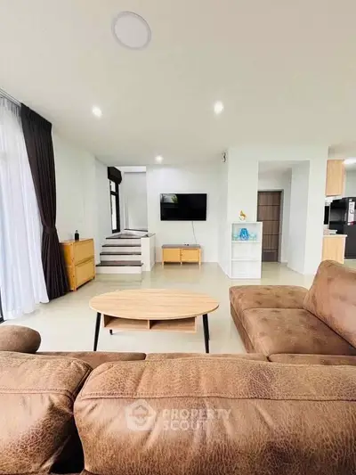 Spacious modern living room with cozy brown sofa and wall-mounted TV, perfect for relaxation.