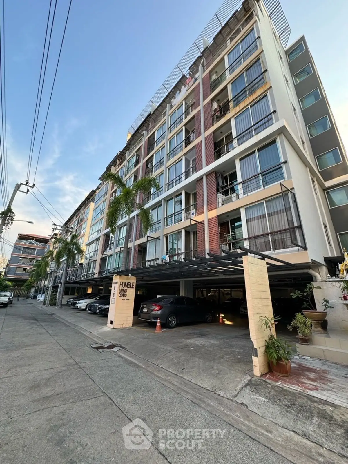 Modern multi-story residential building with parking and palm trees.