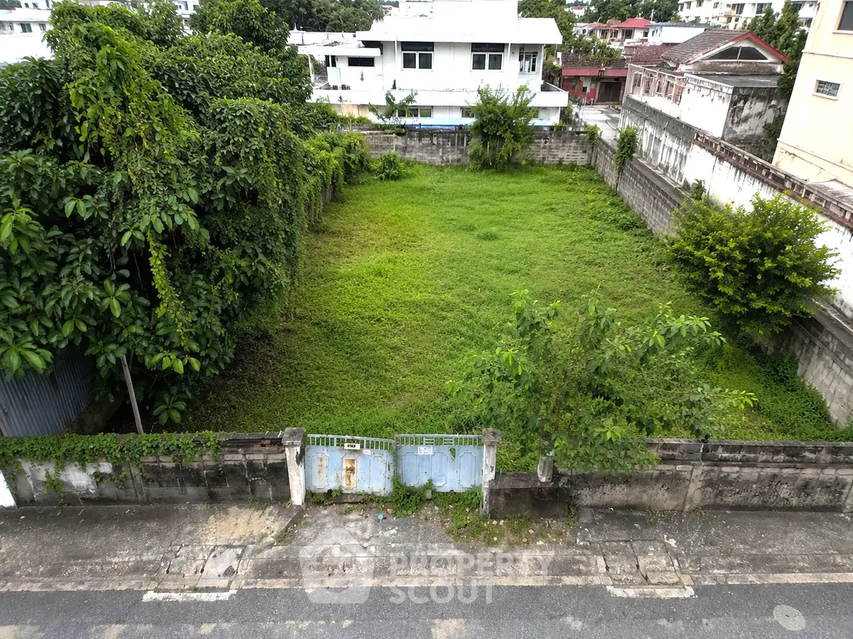 Prime urban land plot with lush greenery, perfect for development in a thriving neighborhood.