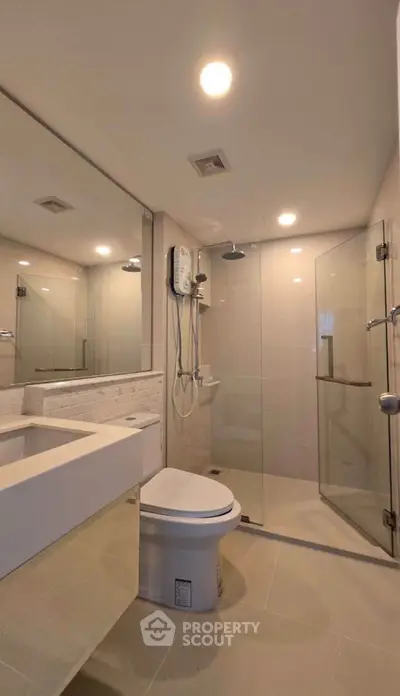 Modern bathroom with glass shower and sleek fixtures in contemporary home.