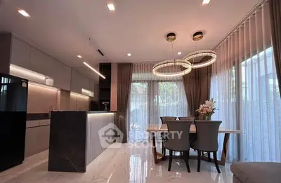 Modern kitchen with elegant dining area and stylish lighting fixtures.